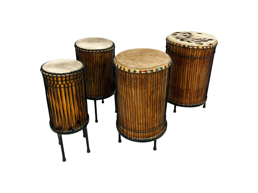 Four African djun-djun bass drums — kenkeni, sangban, and doundounba — on stands with cowhide heads and rope tuning